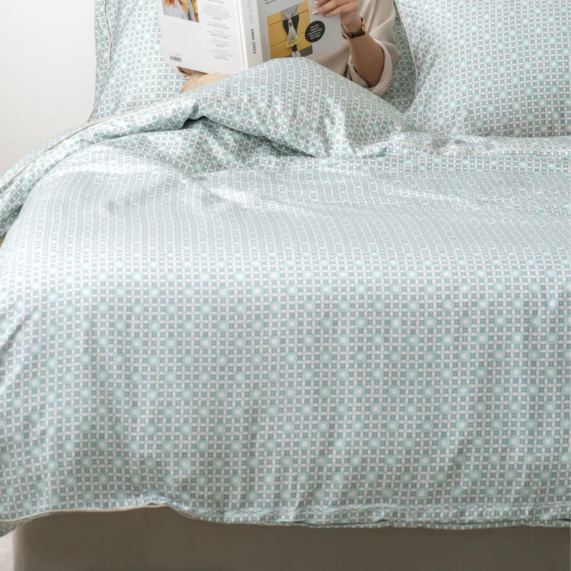 Reading in bed on mint patterned sheets